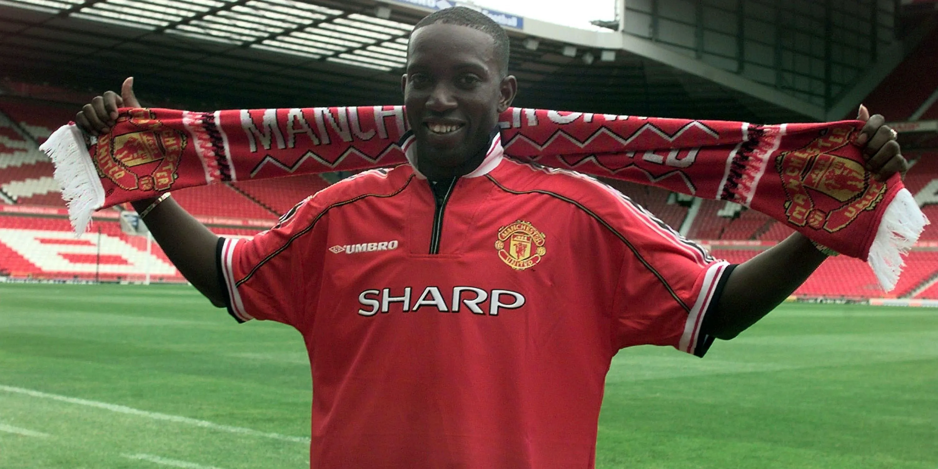 Dwight Yorke giơ cao chiếc khăn quàng Manchester United sau khi ký hợp đồng